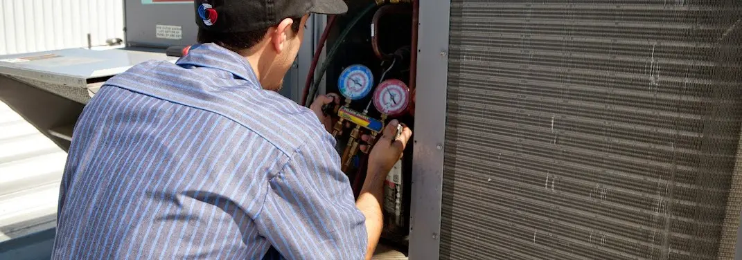 HVAC technician servicing a condenser unit in State College